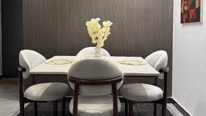 A dining area with a table set for four, a vase with flowers, and a painting on the wall. - Urban stays (Nairobi)