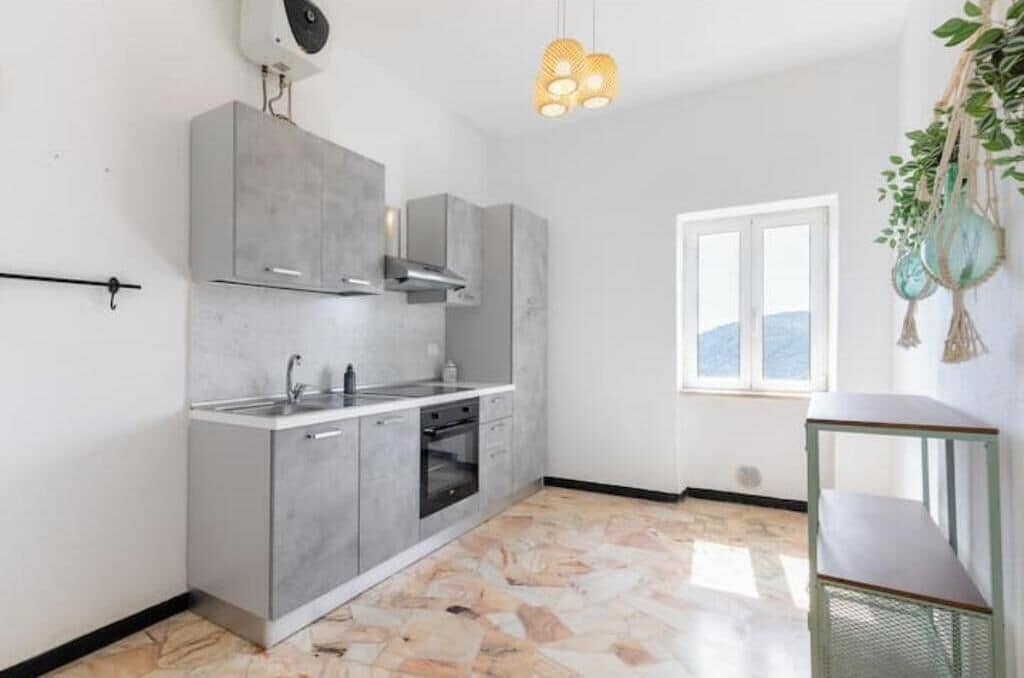A kitchen with grey cabinets, a sink, and a window.