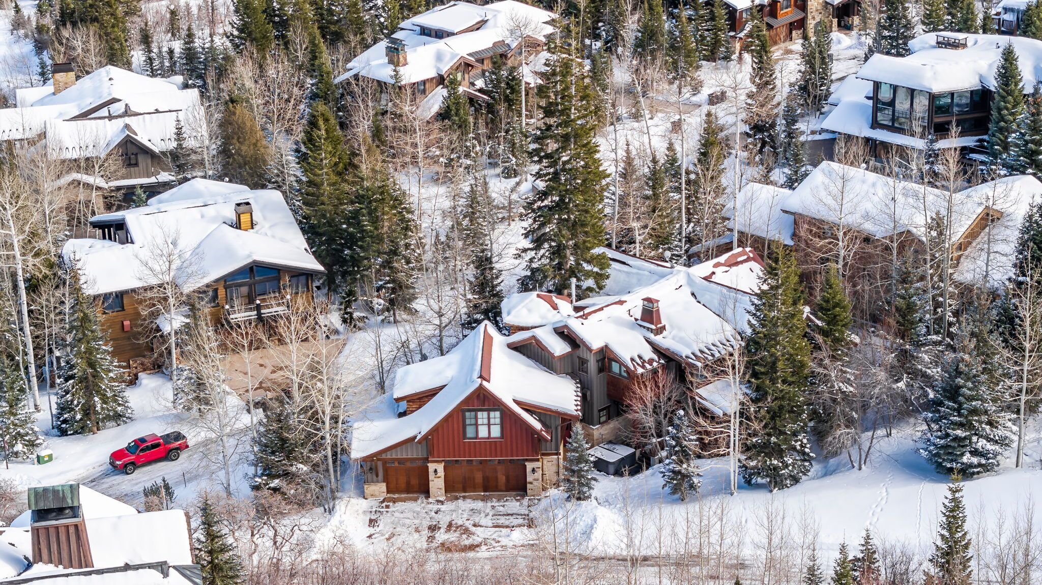 Un groupe de chalets en bois, entourés d’arbres couverts de neige.