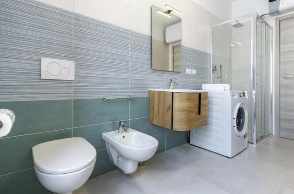 Ein modernes Badezimmer mit Toilette, Bidet, Waschbecken und Waschmaschine.