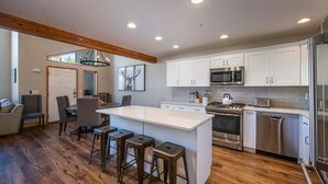 Une cuisine moderne avec des armoires blanches, des appareils en acier inoxydable et un plancher en bois.