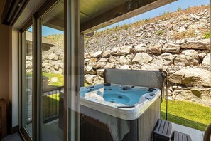 Ein Whirlpool mit Steinwand und einer Rasenfläche im Hintergrund.
