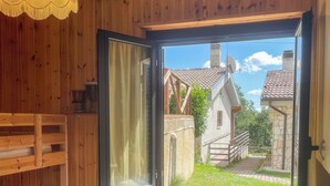 Ein Zimmer mit Holzboden, einem Bett, einem Fenster und Blick auf ein Haus.