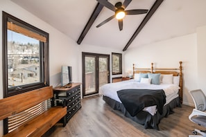 Ein Schlafzimmer mit einem großen Bett, einer hölzernen Bank, einem Schreibtisch und einem Deckenventilator.