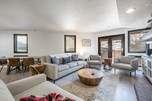 Ein geräumiges Wohnzimmer mit einer Couch, Sesseln, einem Couchtisch und einem Essbereich mit Stühlen und Tisch.