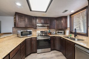 Eine moderne Küche mit dunklen Holzschränken, Edelstahlgeräten, Granitarbeitsplatten und einem Oberlicht.