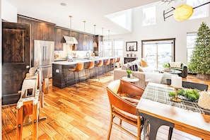 A modern kitchen with dark wood cabinets, stainless steel appliances, and a central island with bar stools. - Spacious 4BR, 4.5BA retreat in Deer Valley with stunning mountain views. (Hideout)