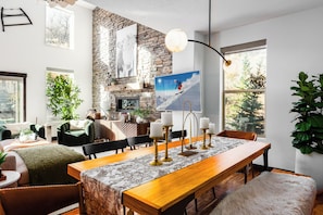 A dining area with a long wooden table, chairs, and a chandelier. - Spacious 4BR, 4.5BA retreat in Deer Valley with stunning mountain views. (Hideout)