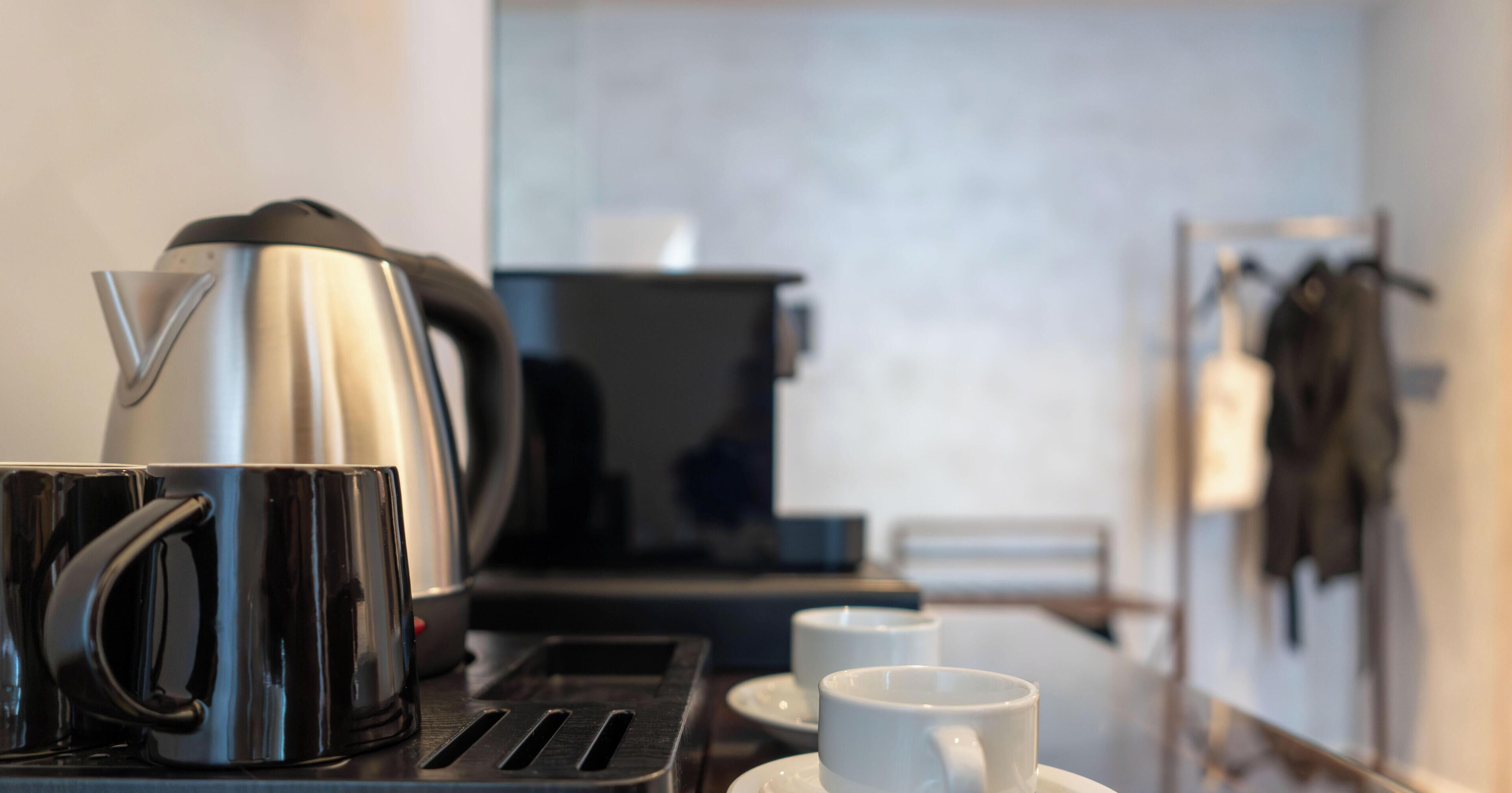 Een kitchenette met een koffiezetapparaat, een broodrooster en een kop koffie op een tafel.