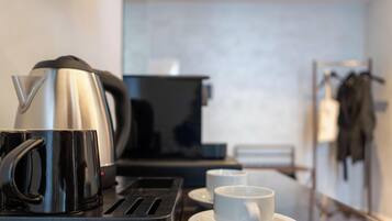 Een kitchenette met een koffiezetapparaat, een broodrooster en een kop koffie op een tafel.