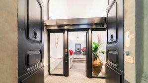 Eine Hotelhalle mit modernem Design, inklusive einer zentralen Doppeltür, einem Blumentopf und einer Treppe, die in den oberen Bereich führt.