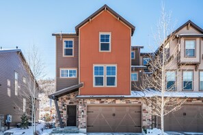 A two-story house with a garage, a brick facade, and a snow-covered ground. - Charming 5BR mountain retreat in Deer Valley, Park City, perfect for 14 guests. (Hideout)