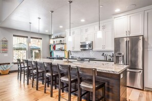 A modern kitchen with a central island, stainless steel appliances, and bar stools. - Charming 5BR mountain retreat in Deer Valley, Park City, perfect for 14 guests. (Hideout)