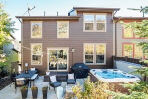 Et toetagers hus med en patio, udendørs møbler, jacuzzi og grill med tag.