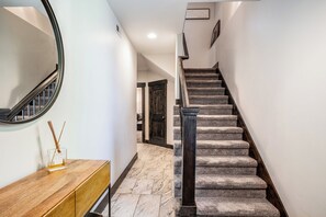 A staircase with a wooden handrail and carpeted steps leading to a room with a wooden console and a mirror. - Luxurious 4-bedroom retreat in Deer Valley, Park City, with hot tub (Hideout)