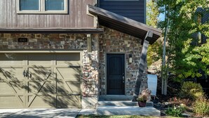 A two-story house with a stone facade, a garage, and a front door. - Luxurious 4-bedroom retreat in Deer Valley, Park City, with hot tub (Hideout)