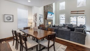 Ein geräumiger Wohnbereich mit Esstisch, grauem Sofa und einer Wand mit Steinverkleidung.