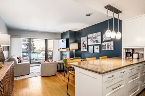 Eine moderne Küche mit einer großen Kochinsel, ein Essbereich mit Tisch und Stühlen sowie ein Wohnzimmer mit Sofa und Couchtisch.