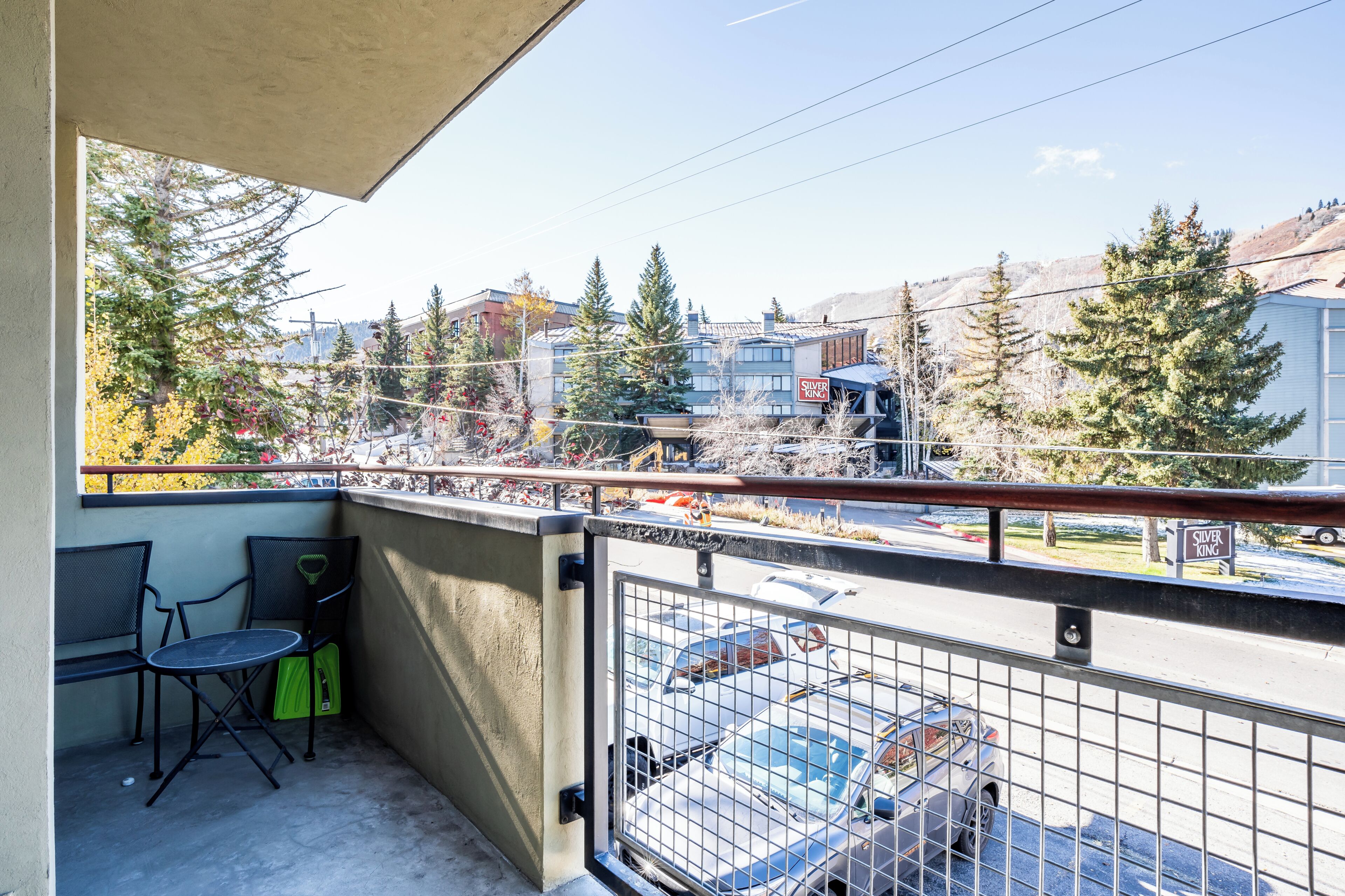 A balcony with a view of a parking lot, a building labeled 'Silver King,' and surrounding trees.