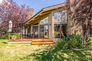 Ein modernes Haus mit einer Terrasse, großen Fenstern und einem Garten mit Blumen.