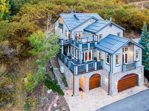 Ein mehrgeschossiges Haus mit Steinfundament, mehreren Balkonen und einer Garage.