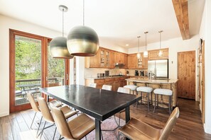 Una cucina moderna con mobili in legno, un'isola centrale con sgabelli e illuminazione a sospensione.