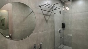 Ein modernes Badezimmer mit rundem Spiegel, Waschbecken, Toilette und einer Duschkabine.