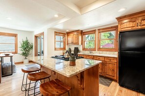 Eine Küche mit Holzschränken, einem schwarzen Kühlschrank, einer Granitarbeitsplatte und einem Blumentopf.