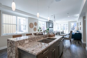 Eine moderne Küche mit Granit-Arbeitsplatten, Spüle und Pendelleuchten.