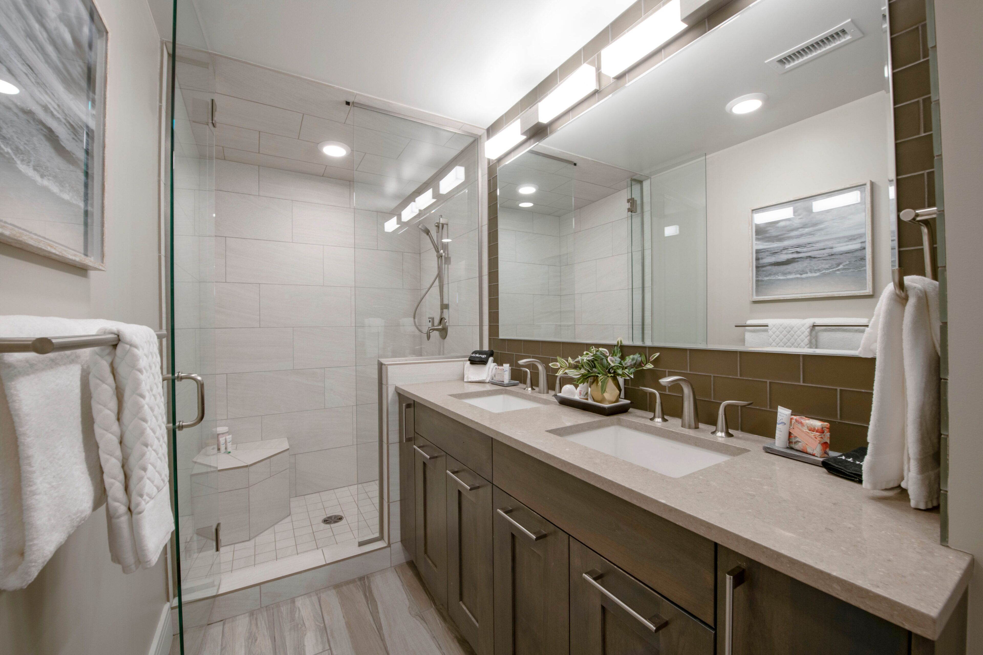 A modern bathroom with a glass-enclosed shower, a double sink vanity, and a large mirror.