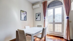 Ein Essbereich mit einem weißen Tisch, vier Stühlen, einem Fenster mit Vorhängen und zwei gerahmten Bildern an der Wand.