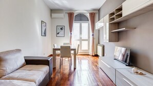 Ein modernes Wohnzimmer mit einer Couch, einem Esstisch, Stühlen, einem Fernseher und Einbauschränken.