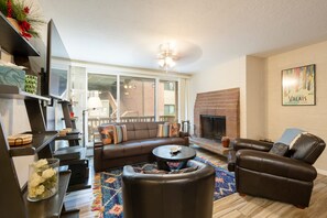 Ein Wohnzimmer mit einer Eckcouch, einem Ledersessel, einem Couchtisch und einem Kamin.