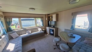 Interior compacto de autocaravana con sofá, una mesita y televisor.