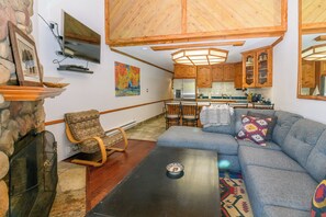 Ein gemütliches Wohnzimmer mit Kamin aus Stein, einem blauen Sofa und einem Holzschaukelstuhl.
