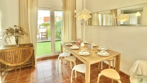 A dining area with a wooden table set for four, a vase with flowers, and a view of the outdoors. - Large terrace 140m from the Mediterranean Sea (Cabo de Palos)