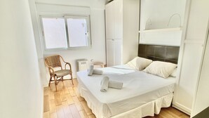 A bedroom with a bed, a chair, a radiator, and a window. - Large terrace 140m from the Mediterranean Sea (Cabo de Palos)