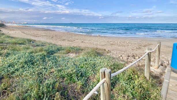 A beach with a wooden boardwalk leading to the water, a distant mountain, and a clear sky. - Large terrace 140m from the Mediterranean Sea (Cabo de Palos)