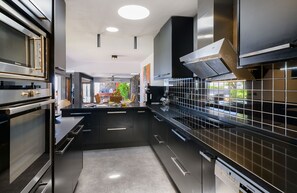 A modern kitchen with stainless steel appliances, black cabinetry, and a tiled backsplash. - Luxury & Harmony, Top luxury villa in playa blanca (Playa Blanca)