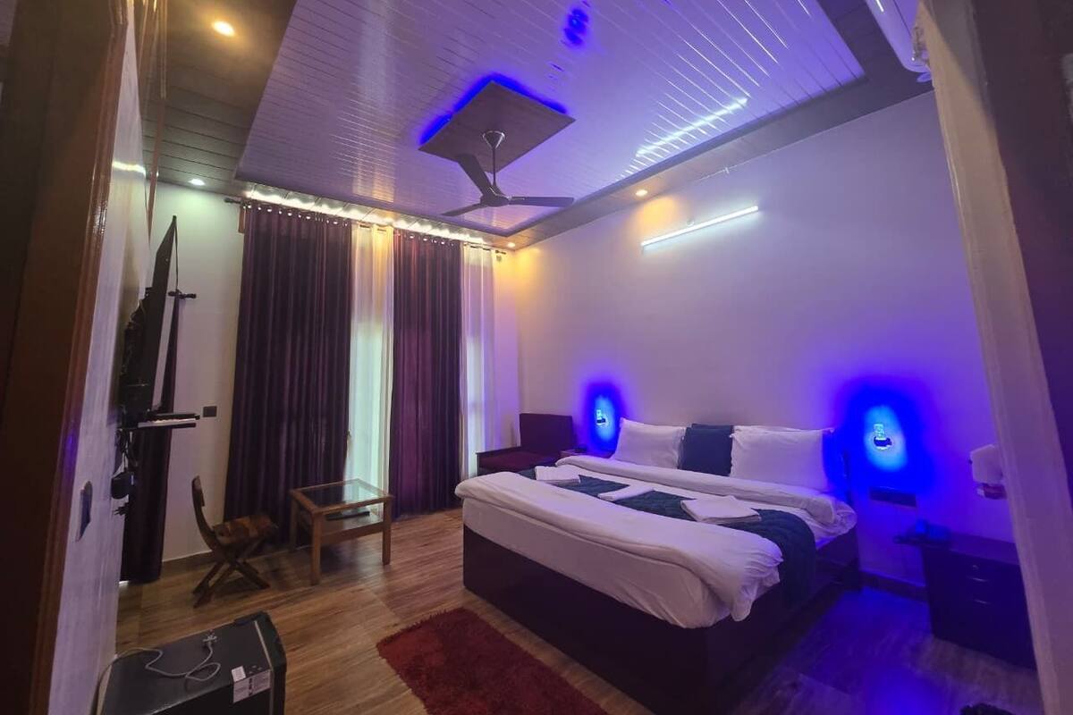 A bedroom with a bed, a desk, a chair, a ceiling fan, and a TV.