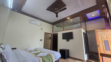 A hotel room with a bed, a ceiling fan, a TV, and a wardrobe.