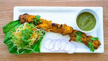 A plate with grilled chicken, a side salad, sliced onions, and a green sauce.
