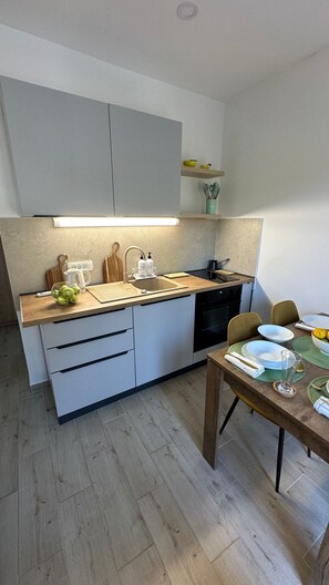 A modern kitchen with a wooden countertop, white cabinets, a dishwasher, and a dining area with a table set for two.