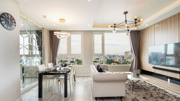 Ein modernes Wohnzimmer mit Essbereich, großen Fenstern, Blick auf die Stadt und einem Flachbildfernseher.
