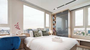 Ein modernes Schlafzimmer mit einem großen Bett, einem Schreibtisch, einem Sessel und einem Bücherregal.