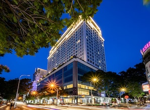 A multi-story hotel with a modern design, featuring a prominent entrance and a well-lit facade. - Luminous Apartment (Ho Chi Minh City)