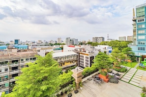 Un jardin sur le toit, agrémenté de plantes en pot, d’un espace salon extérieur et offrant une vue sur le panorama urbain.