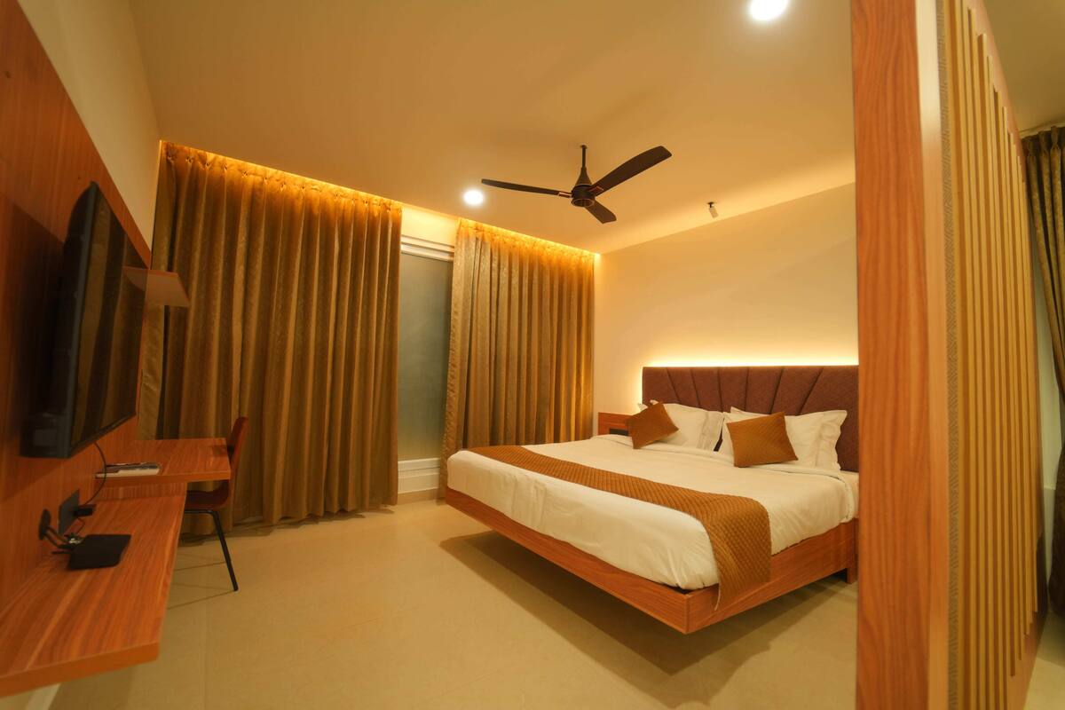 Una habitación de hotel moderna con una cama grande, un escritorio y un ventilador de techo.