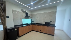 A modern kitchen with a built-in stove, a microwave, and a ventilation hood. - Arunaragha (Mysore)