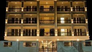 A multi-story hotel with balconies, a gated entrance, and a well-lit facade. - Arunaragha (Mysore)